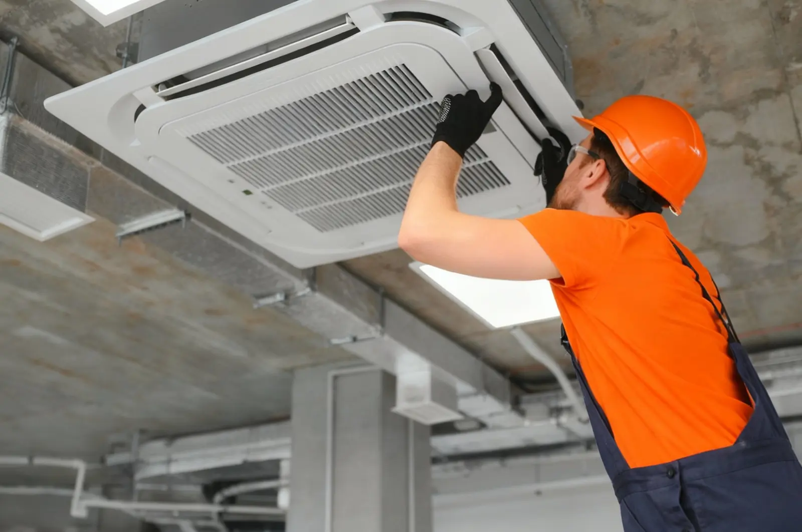 Technician servicing a ceiling-mounted air-conditioning unit