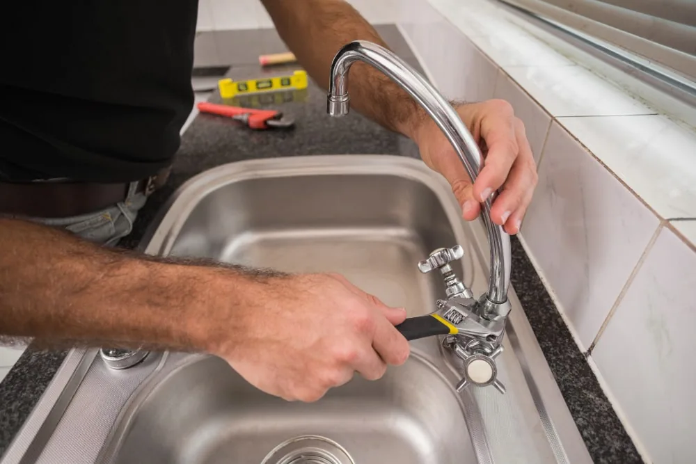 Plumber checking a kitchen sink tap and accessible fittings