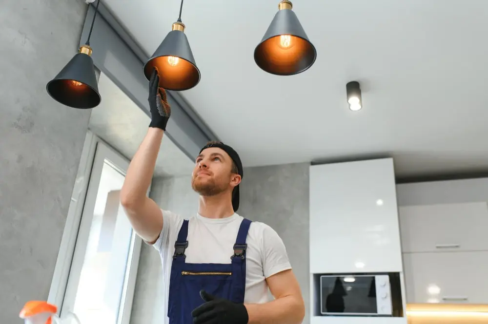 Electrician fitting pendant lighting in a kitchen