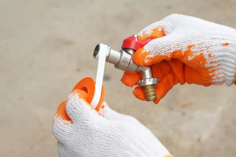 Plumber applying sealant to a pipe fitting for an emergency plumbing route in Burpham