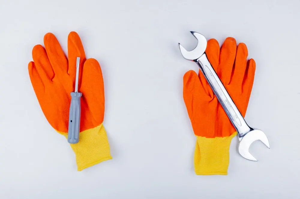 Orange safety gloves and plumbing tools arranged for a service visit