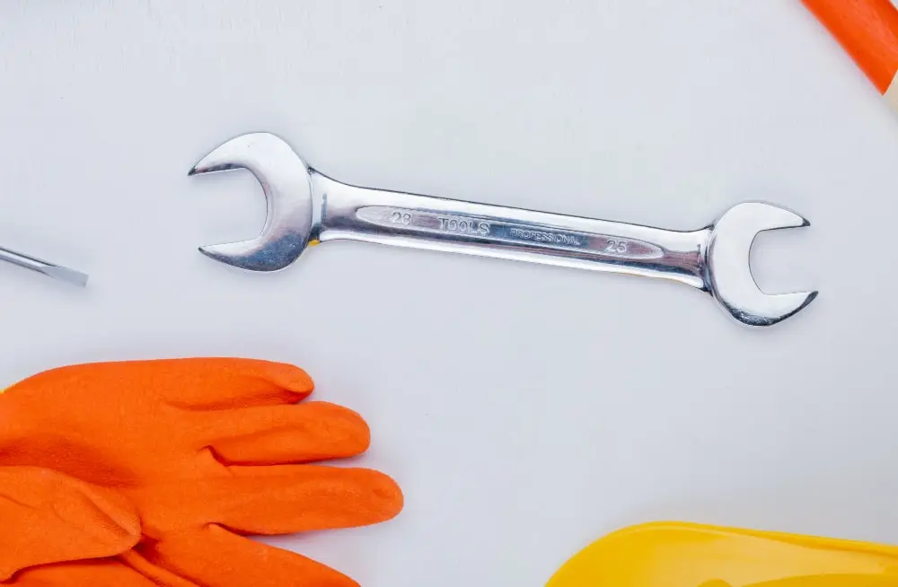 Plumbing spanner and protective gloves laid out before a leak detection visit
