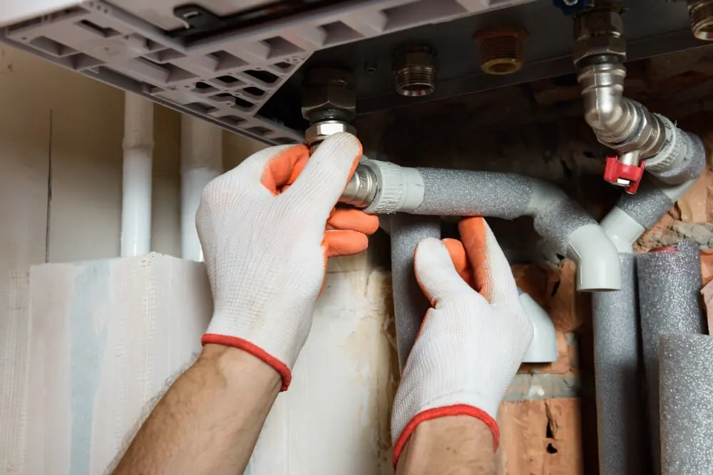 Plumber checking accessible pipe joints before repairing a visible leak