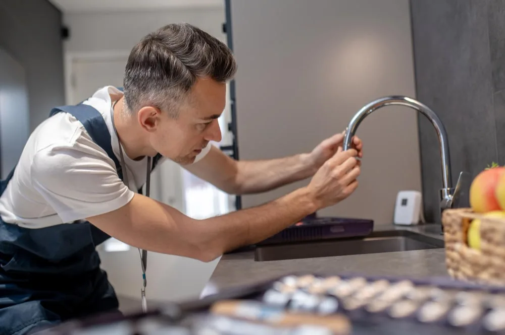 Plumber aligning a chrome tap above a dark sink