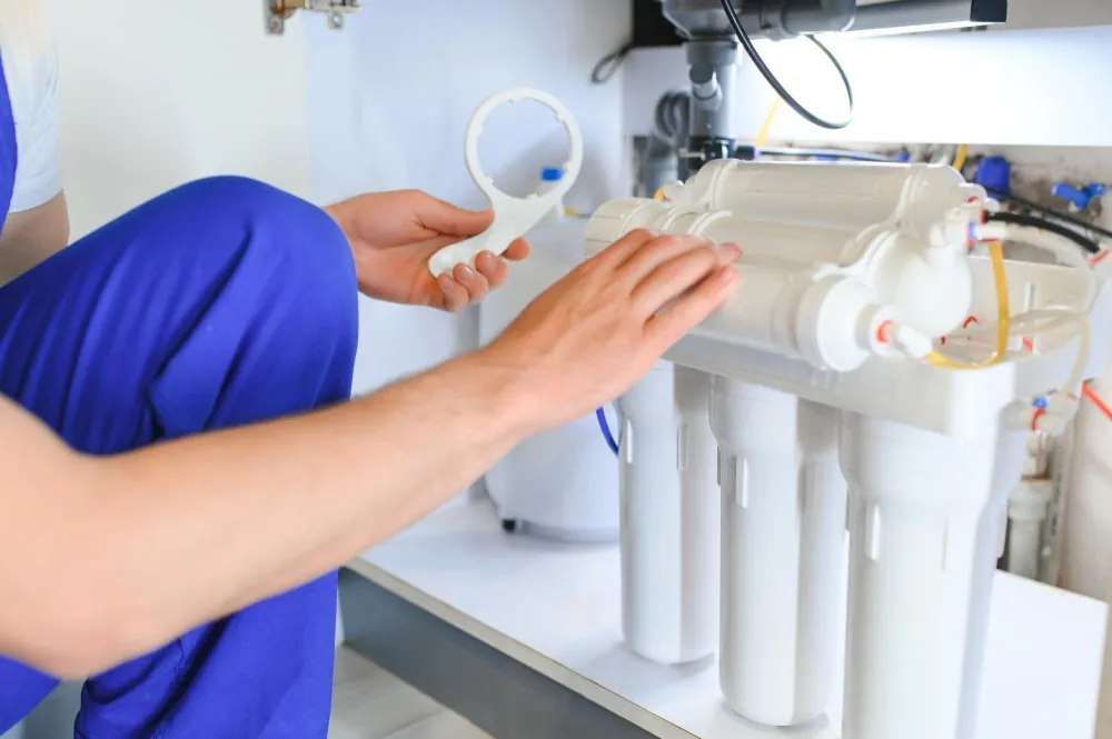 Technician checking a multi-stage water-treatment unit and its connections