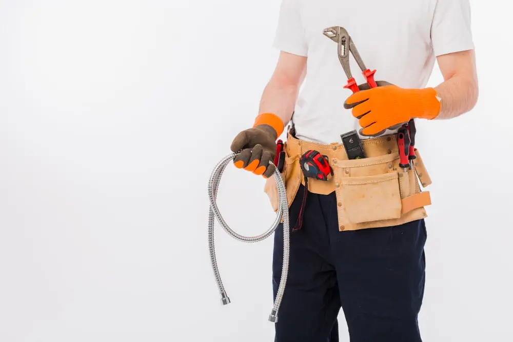 Plumber holding flexible hoses and plumbing installation tools