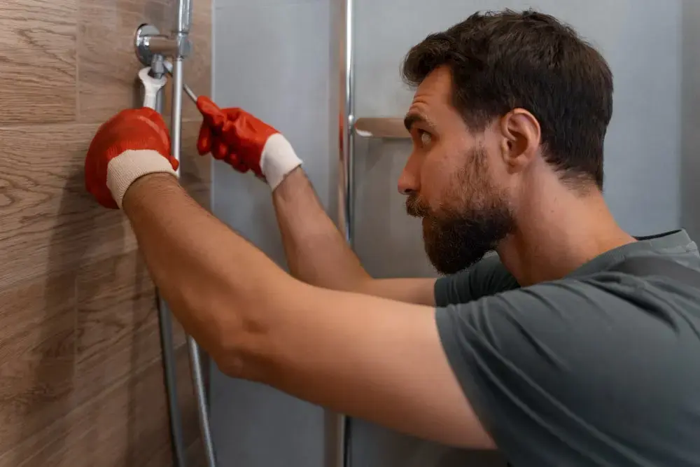 Plumber checking an accessible shower connection against a tiled wall