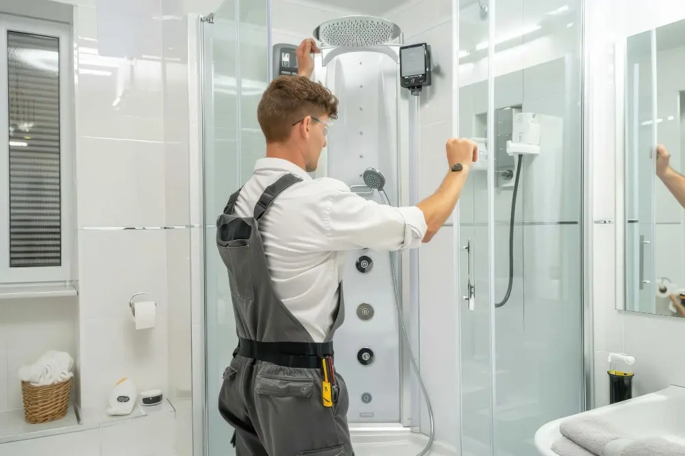 Technician inspecting a shower enclosure, controls and visible fittings