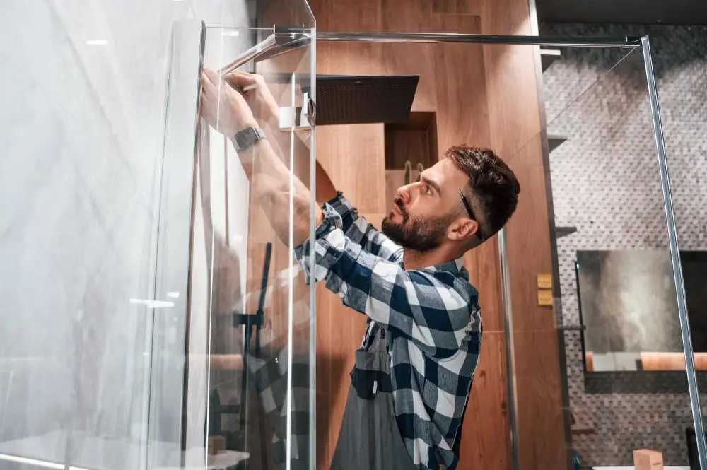 Installer checking the alignment and wall fixing of a glass shower screen