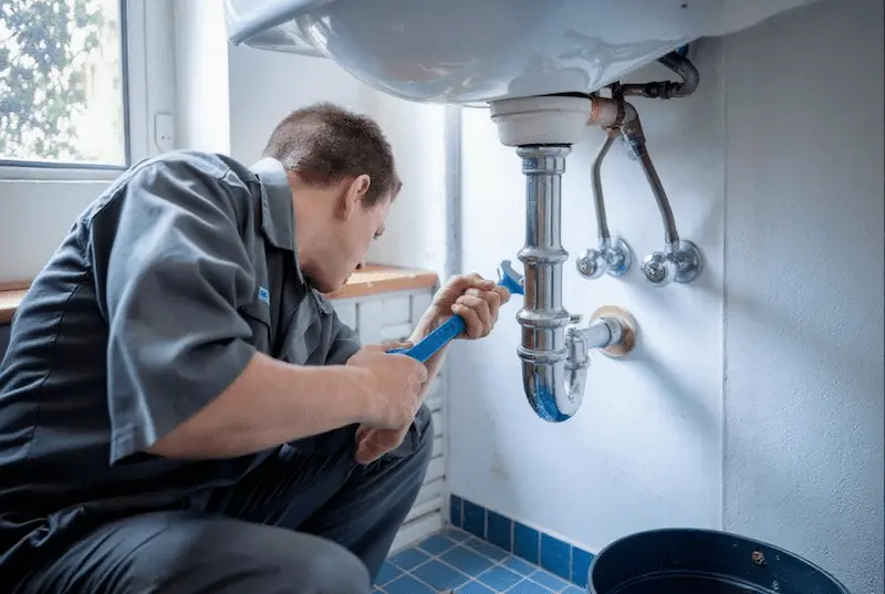Plumber repairing an accessible water leak beneath a basin